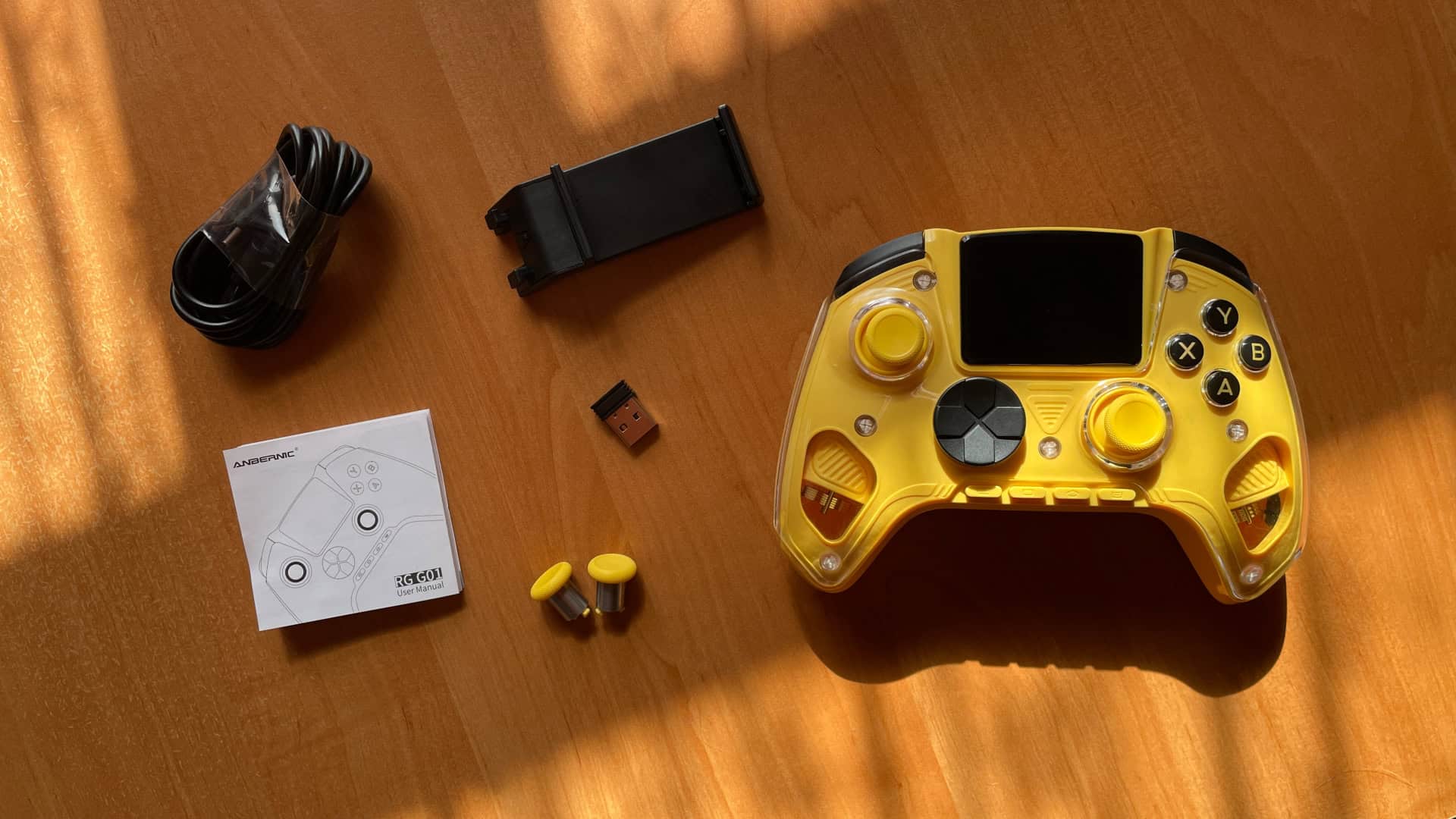 Complete package contents of the Anbernic RG G01 controller, including all included accessories and items laid out together