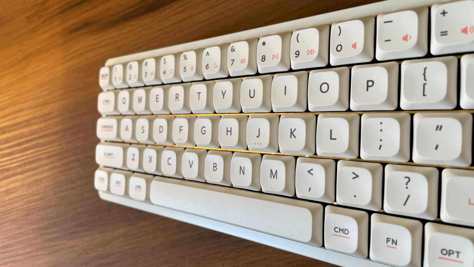 Close-up of the IQUNIX Magi65 mechanical keyboard plate showing premium gold decorative elements, including horizontal gold traces visible between the key spaces, emphasizing its refined design.