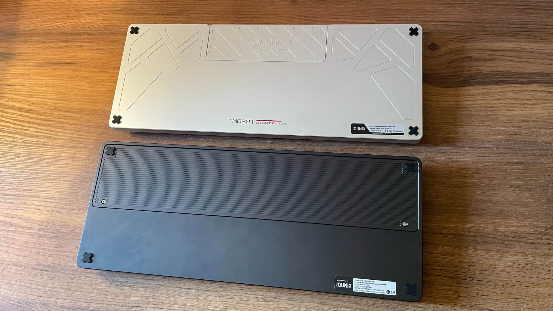 Side-by-side view of the IQUNIX Magi75 and IQUNIX MQ80 mechanical keyboards placed upside down, showing the bottom.