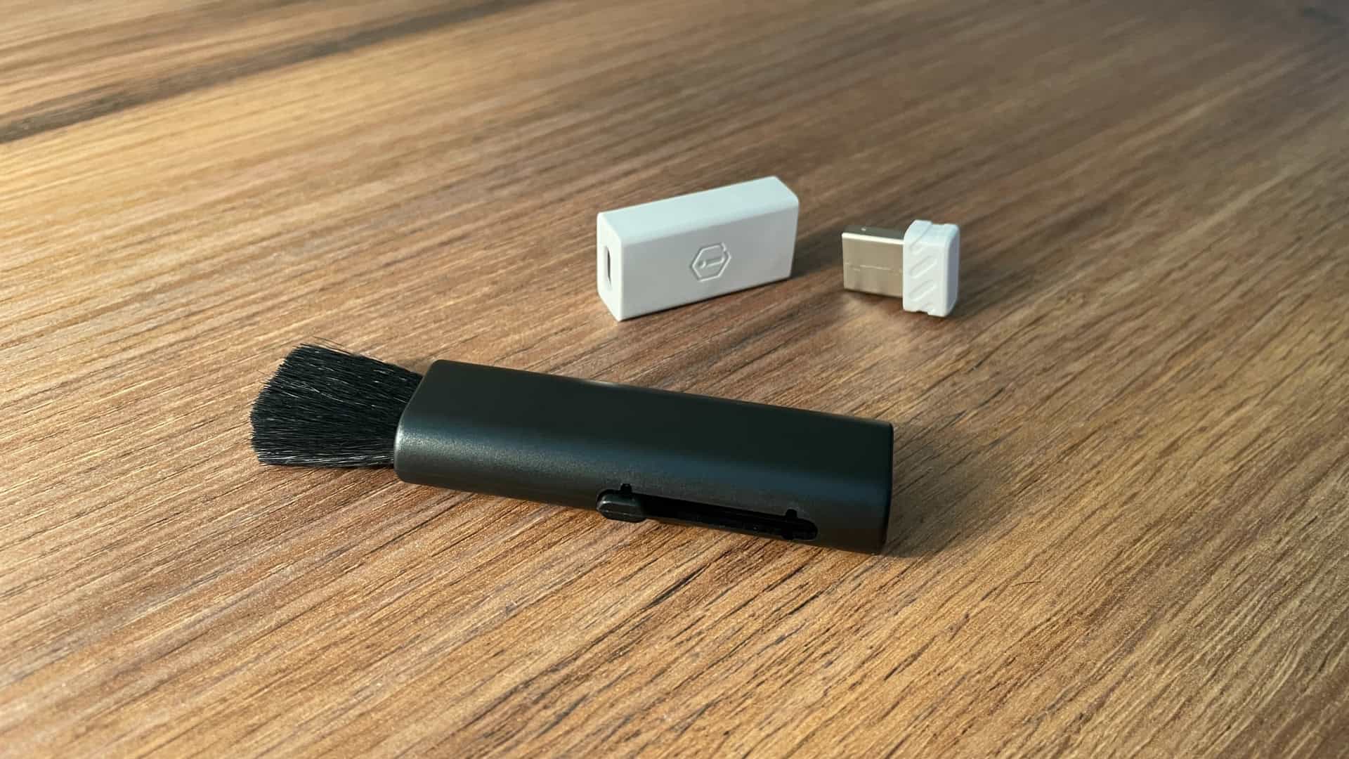 Close-up of IQUNIX MQ80 accessories showing a cleaning brush, wireless dongle, and USB-C to USB-A converter.