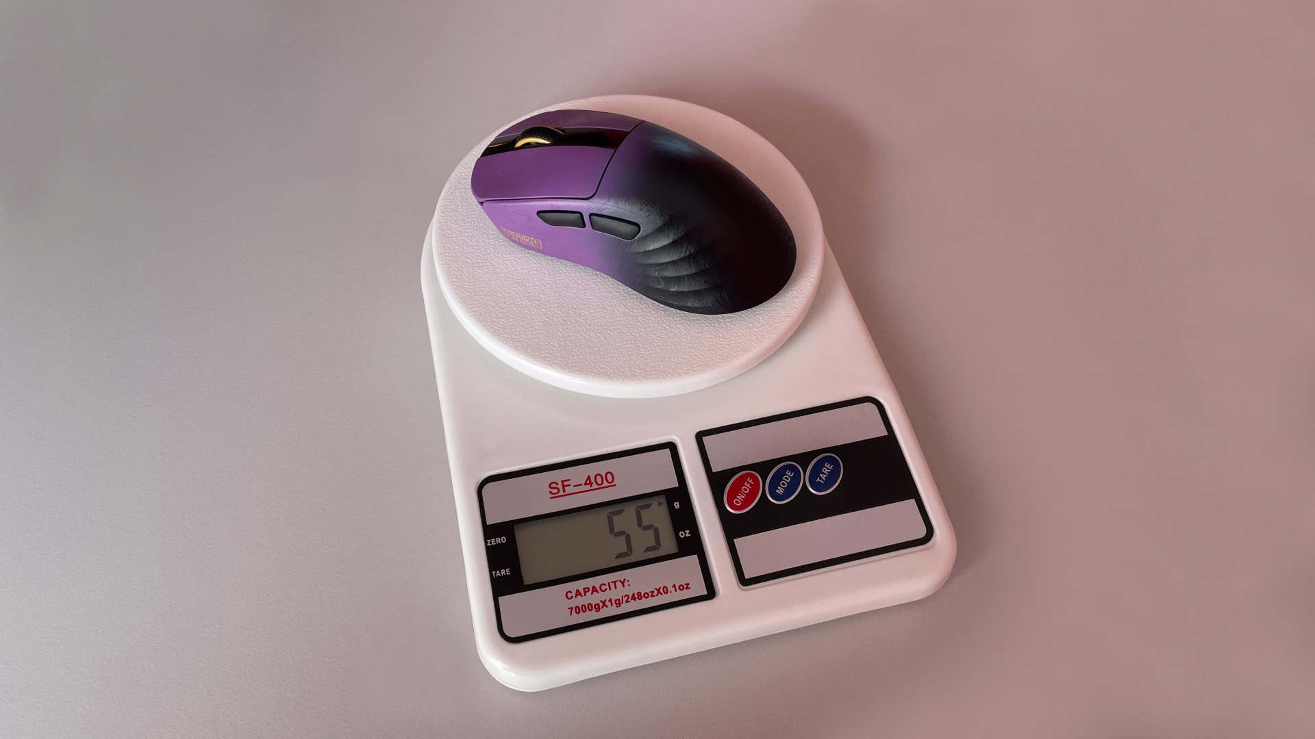 The Epomaker Carbonis gaming mouse placed on a digital scale to measure its weight.