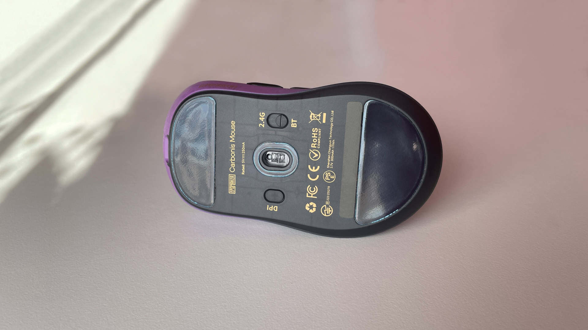 Bottom view of the Epomaker Carbonis gaming mouse showing the PTFE skates, sensor, and underside design.