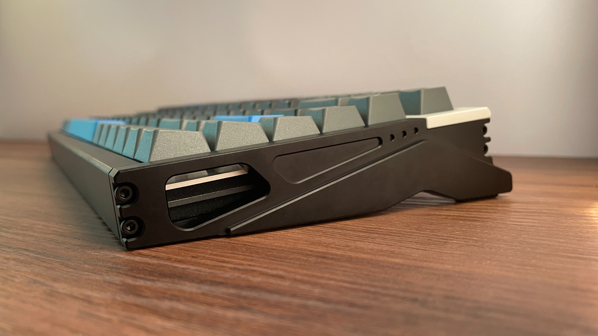 IQUNIX EZ75 Review – Gaming Performance Without Compromise 10 Side profile of the IQUNIX EZ75 showing the sculpted CNC-machined aluminum case, exposed screws, and the opening that reveals part of the internal plate, PCB, and foam layers.