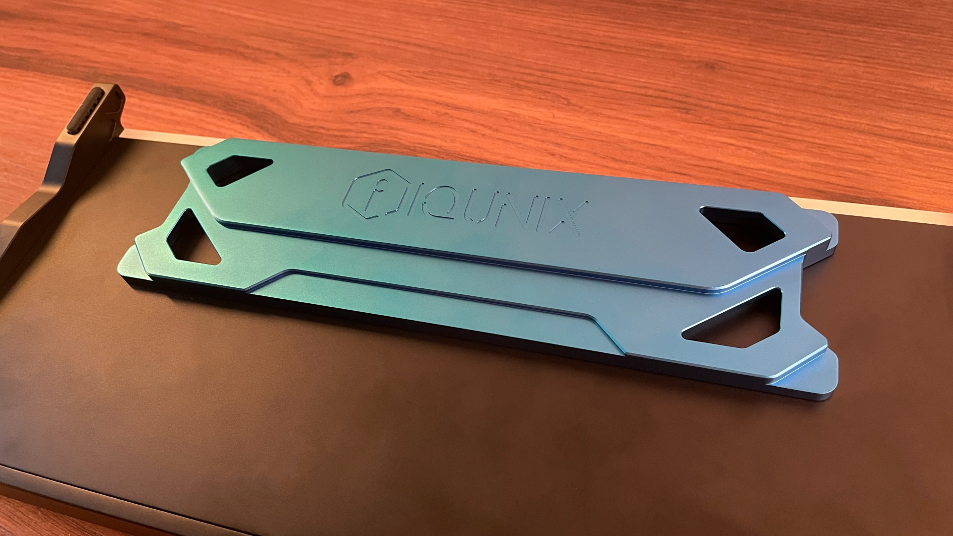 IQUNIX EZ75 Review – Gaming Performance Without Compromise 28 Close-up of the blue anodized aluminum centerpiece on the underside of the IQUNIX EZ75, with light reflecting across the machined surface and highlighting the finish.