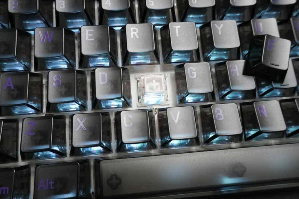 Close-up of a translucent MADE68 Ultra V2 keycap next to the exposed switch stem, along with the included Print keycap