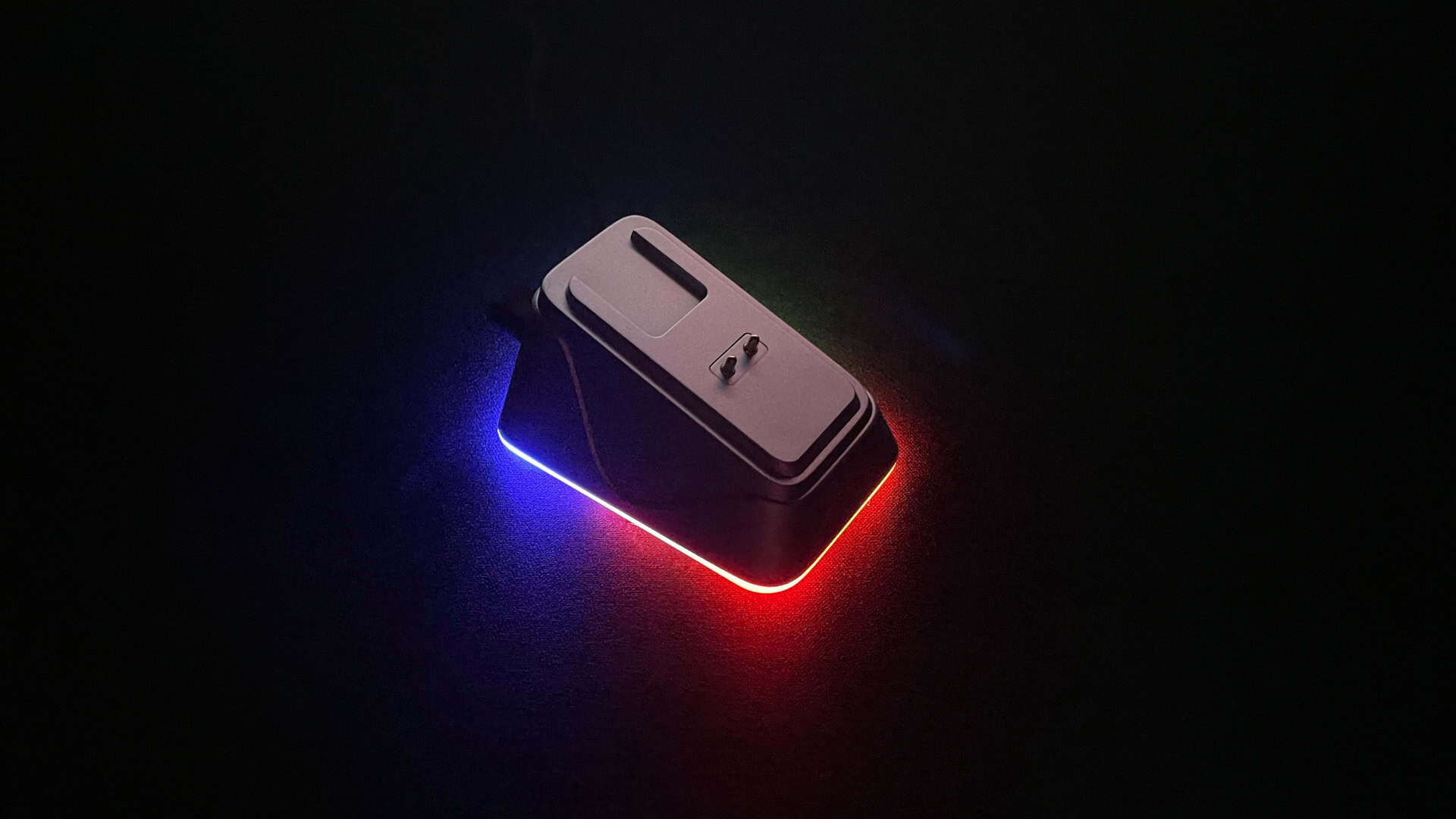 Epomaker Nex Pro charging dock glowing with its RGB lighting in a dark room.
