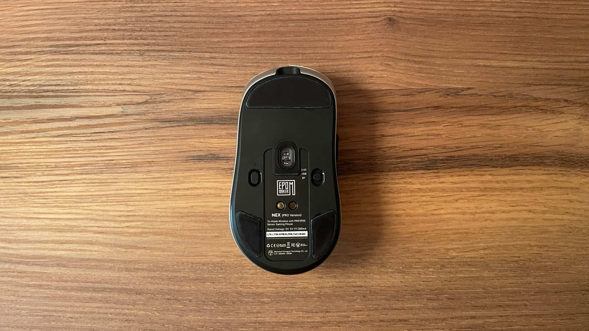 Bottom view of the Epomaker Nex Pro ergonomic gaming mouse, showing the optical sensor, PTFE feet, and power switch.