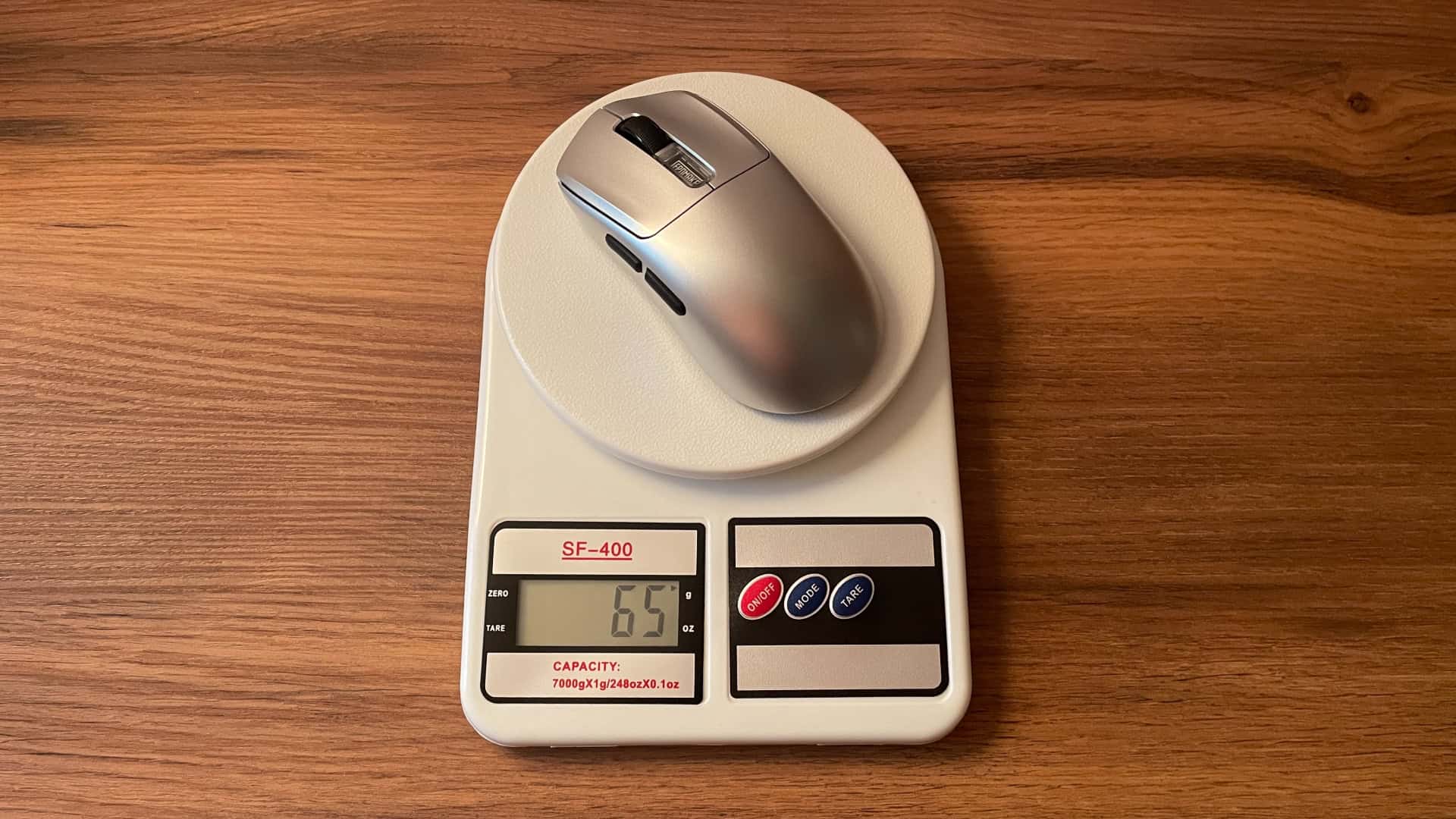The Epomaker Nex Pro ergonomic gaming mouse placed on a digital scale to measure its weight.