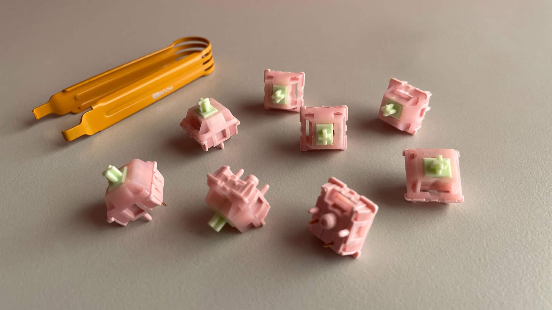 KiiBoom x Strawberryjam1986 Strawberry Jello switches scattered across a desk, showing their pink housings and green stems.