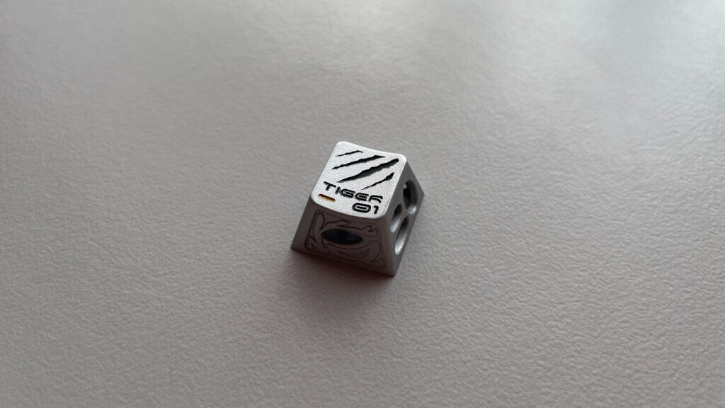 Close-up of an aluminum artisan keycap with an artistic design and detailed surface work.