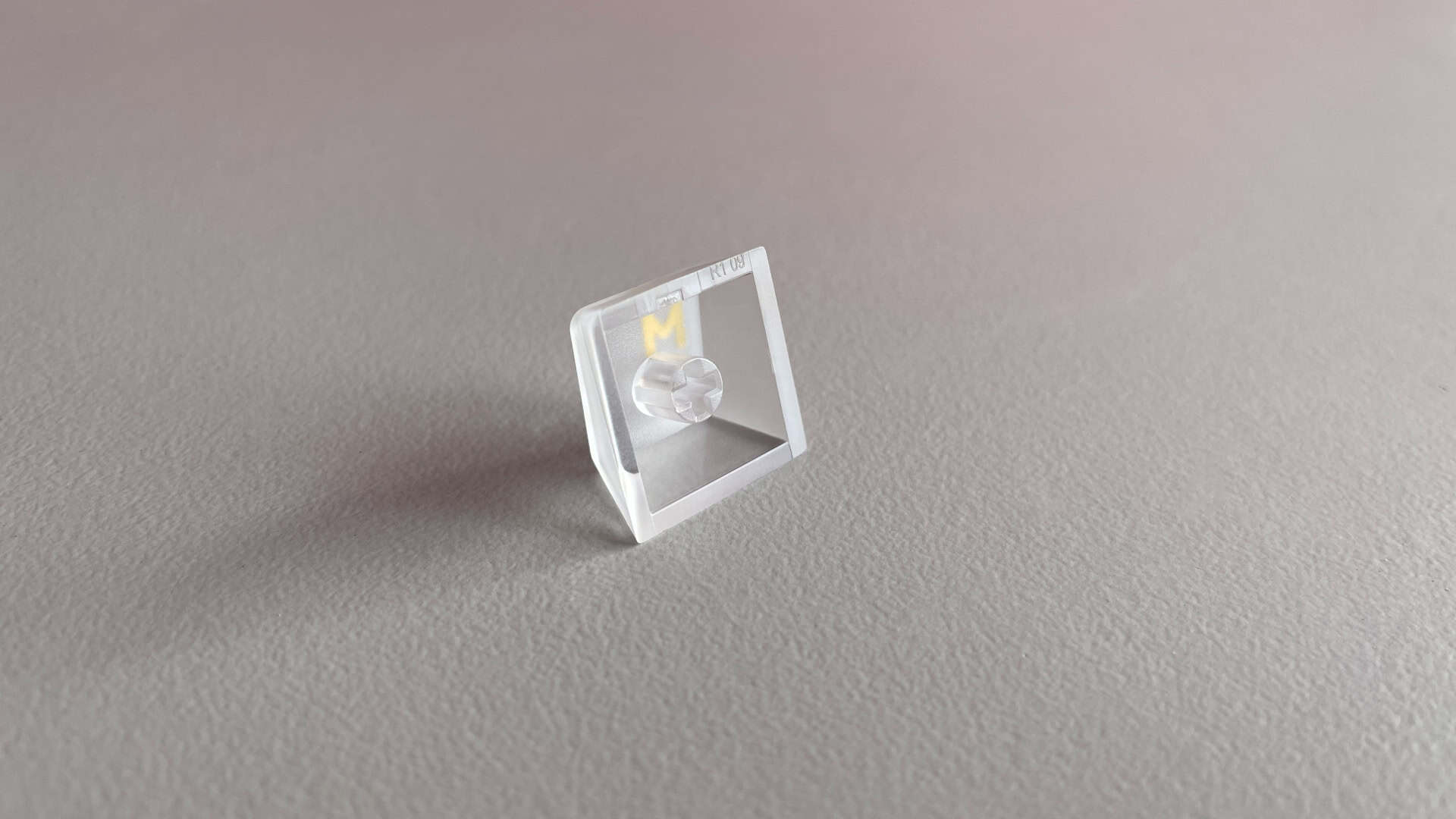 A translucent PC keycap shown upside down to reveal its stem and 1.7 mm wall thickness.