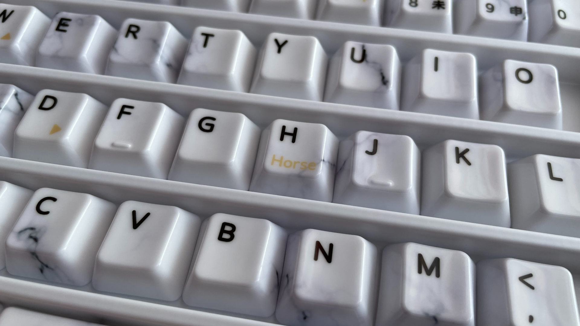 XVX Ceramic Keycaps Review: Year of the Horse Keycap Set 10 H keycap from the XVX Year of the Horse set with the word “Horse” printed on it.